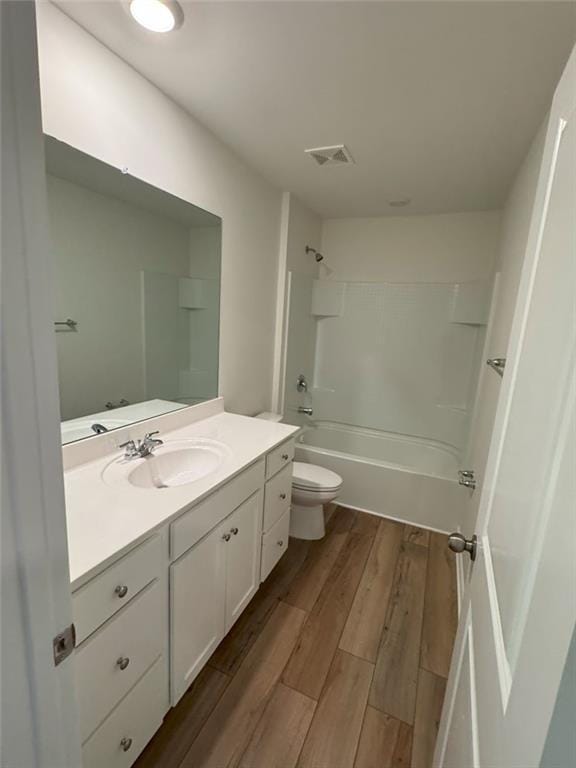 bathroom with visible vents, toilet, washtub / shower combination, vanity, and wood finished floors