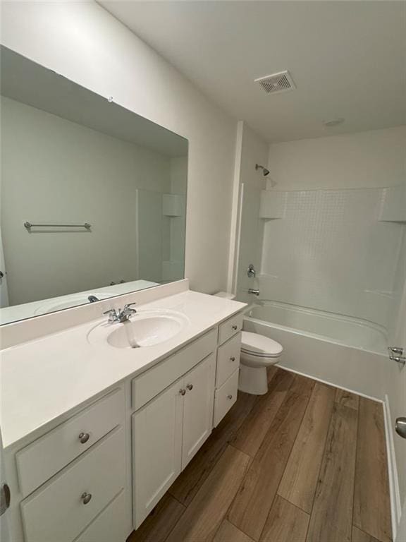 full bath with toilet, shower / bath combination, wood finished floors, vanity, and visible vents