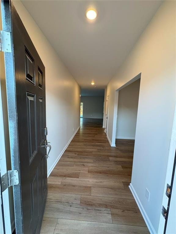 corridor with light wood-style floors and baseboards