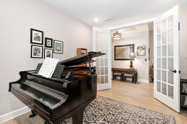 miscellaneous room with hardwood / wood-style flooring, an inviting chandelier, and french doors