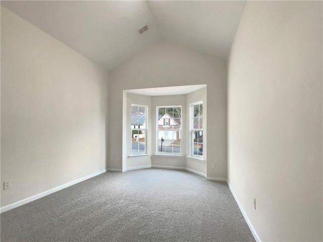 carpeted empty room featuring vaulted ceiling