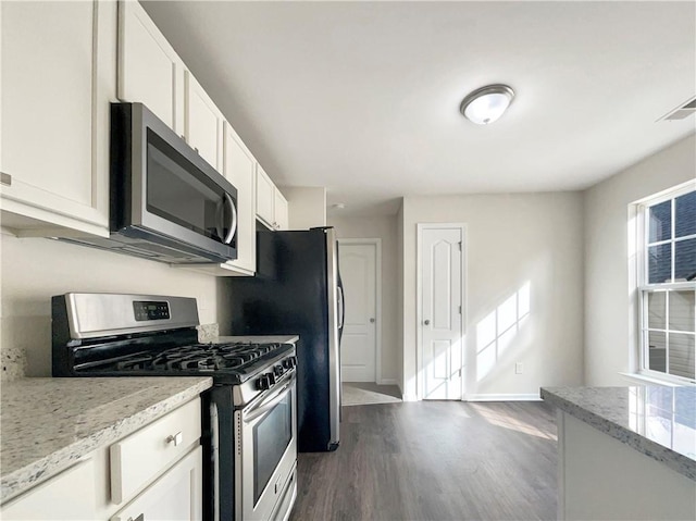 kitchen featuring stainless steel appliances, white cabinetry, dark hardwood / wood-style floors, and light stone counters