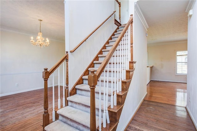 staircase with hardwood / wood-style floors, crown molding, and a chandelier