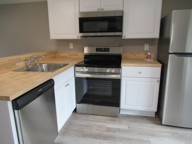 kitchen with white cabinetry, appliances with stainless steel finishes, light hardwood / wood-style floors, and sink