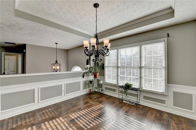 unfurnished dining area with a tray ceiling, wainscoting, a notable chandelier, and hardwood / wood-style flooring