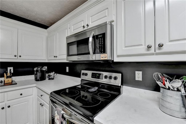 kitchen with stainless steel appliances, light countertops, and white cabinetry