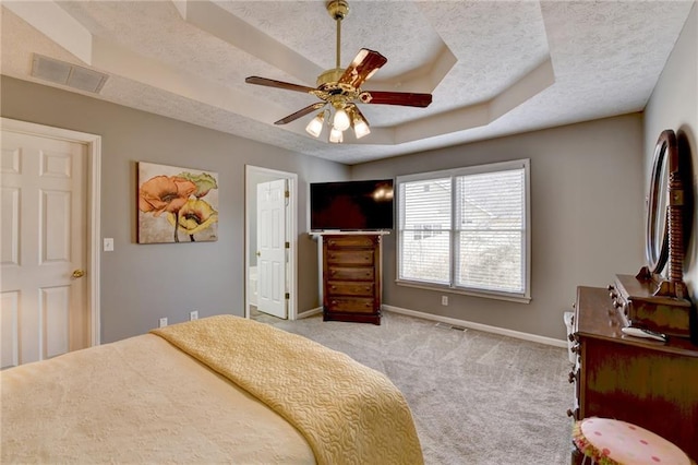 bedroom featuring baseboards, a raised ceiling, a textured ceiling, and light colored carpet