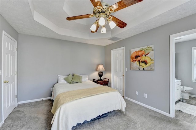 carpeted bedroom with a tray ceiling, visible vents, a textured ceiling, and baseboards