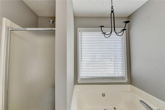 bathroom with a stall shower, a jetted tub, and a textured ceiling