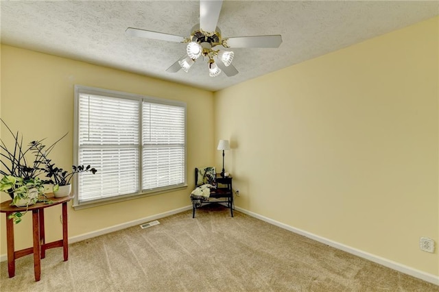 living area with a textured ceiling, carpet floors, ceiling fan, and baseboards