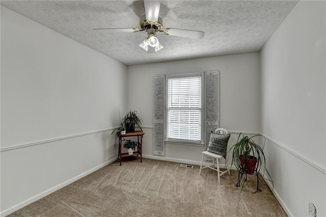 unfurnished room featuring ceiling fan, a textured ceiling, carpet flooring, visible vents, and baseboards