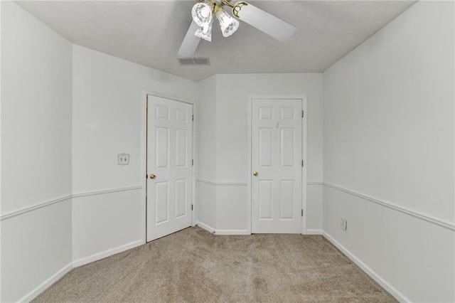 spare room featuring visible vents, baseboards, ceiling fan, carpet, and a textured ceiling