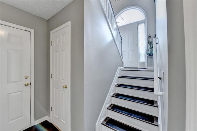 entryway with stairway and a textured ceiling