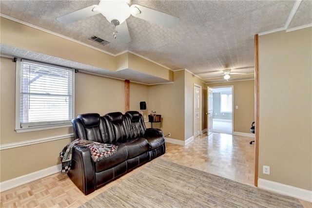 living room featuring ornamental molding, visible vents, a textured ceiling, and baseboards