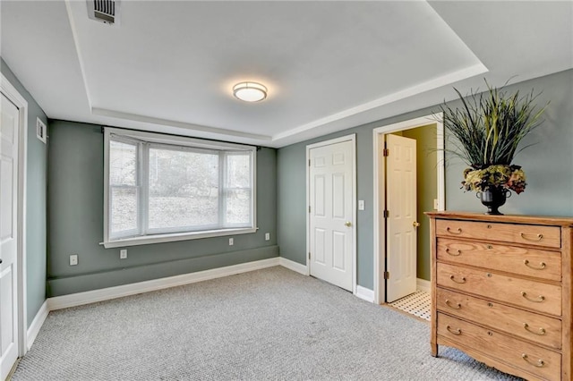 carpeted bedroom featuring baseboards, visible vents, and a tray ceiling