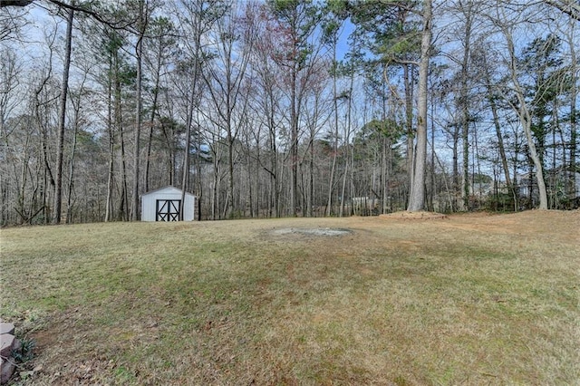 view of yard with a storage shed, an outdoor structure, and a view of trees