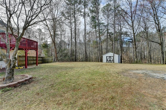 view of yard with a wooden deck, a storage unit, and an outbuilding