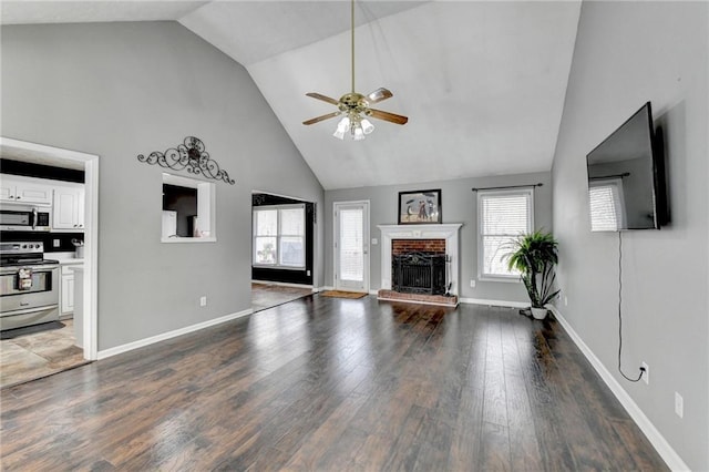 unfurnished living room featuring ceiling fan, high vaulted ceiling, a fireplace, wood finished floors, and baseboards