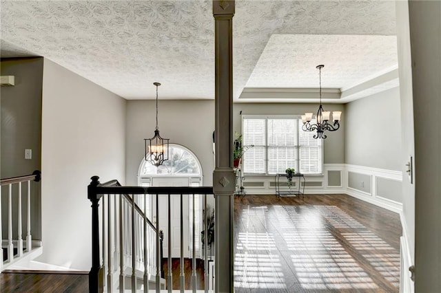 interior space with wood finished floors, an upstairs landing, and an inviting chandelier