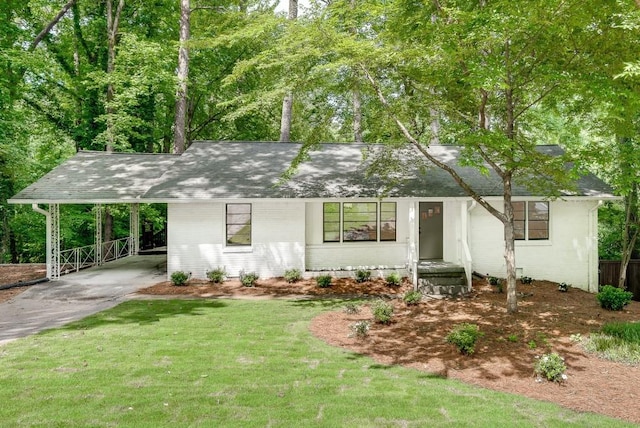 ranch-style house featuring a shingled roof, concrete driveway, a front lawn, a carport, and brick siding