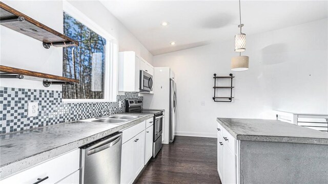 kitchen with appliances with stainless steel finishes, white cabinetry, backsplash, and decorative light fixtures