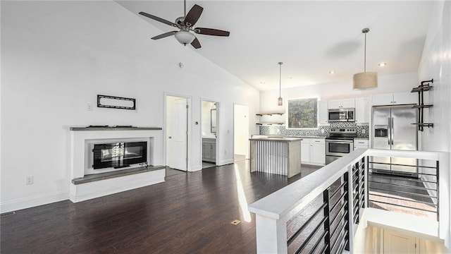 kitchen with appliances with stainless steel finishes, dark hardwood / wood-style flooring, white cabinets, hanging light fixtures, and decorative backsplash