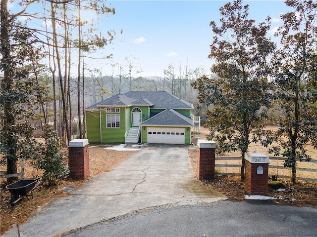 view of front facade with driveway, an attached garage, and fence