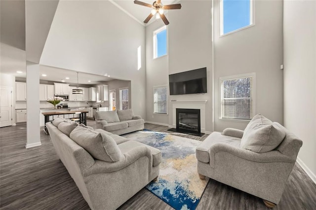 living room with ceiling fan, dark wood-type flooring, and a high ceiling