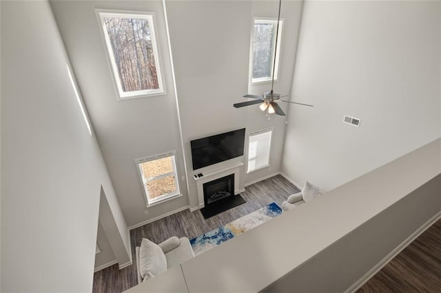 living room with ceiling fan, plenty of natural light, and dark wood-type flooring