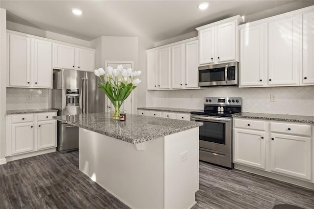 kitchen featuring white cabinets, appliances with stainless steel finishes, a center island, and stone counters