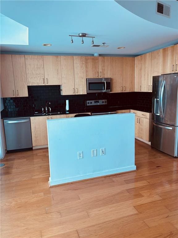 kitchen with decorative backsplash, stainless steel appliances, sink, and light hardwood / wood-style flooring