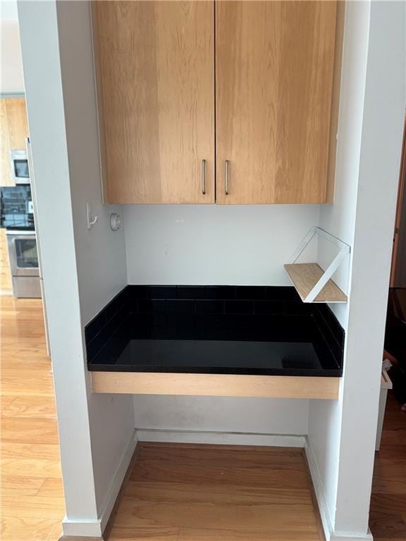 room details featuring stainless steel appliances, hardwood / wood-style floors, and backsplash