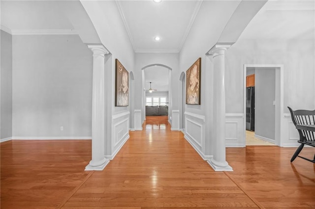 corridor with ornamental molding, decorative columns, and light hardwood / wood-style floors