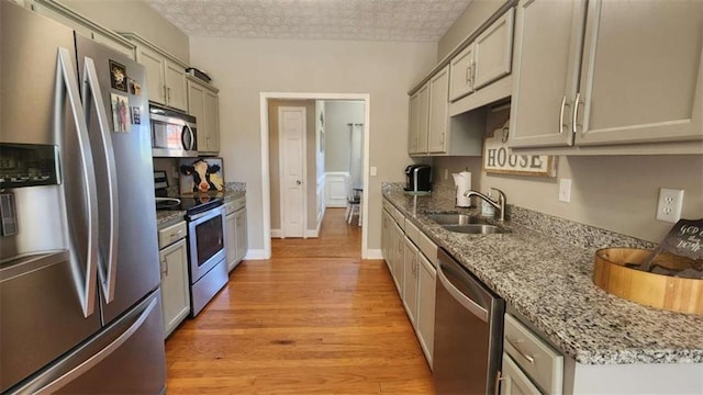 116 Ridge Xing, Temple, GA 30179 - kitchen with light stone counters, a textured ceiling, appliances with stainless steel finishes, light wood finished floors, and a sink