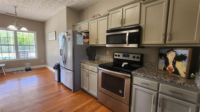 116 Ridge Xing, Temple, GA 30179 - kitchen with light wood finished floors, an inviting chandelier, gray cabinetry, and stainless steel appliances