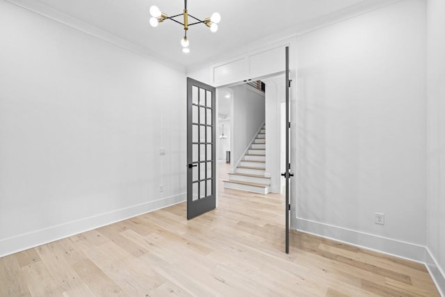 spare room with an inviting chandelier, light hardwood / wood-style flooring, and ornamental molding