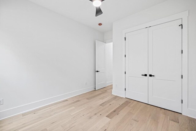 unfurnished bedroom with light wood-type flooring, ceiling fan, and a closet