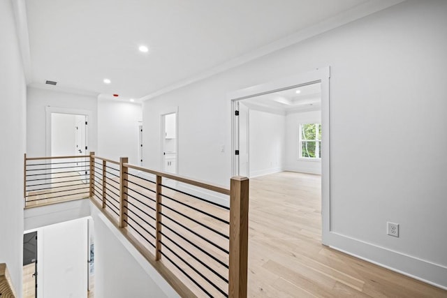 hallway with ornamental molding and light hardwood / wood-style flooring