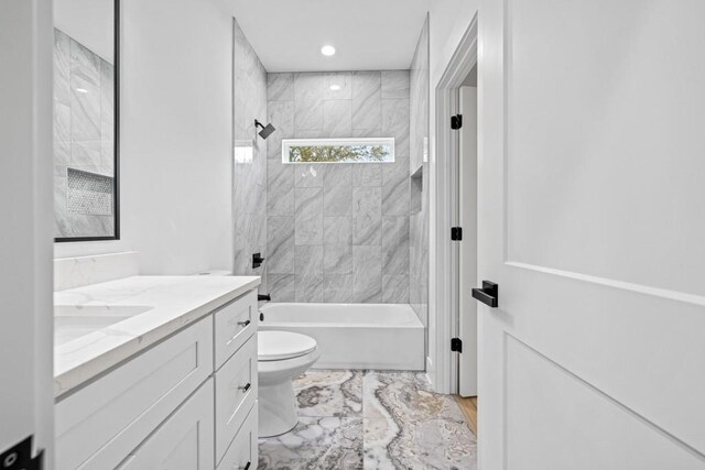 full bathroom featuring toilet, tiled shower / bath combo, and vanity