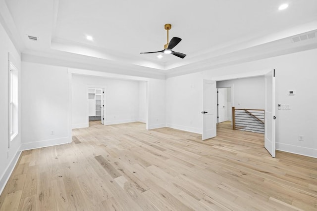 unfurnished living room with ceiling fan, light hardwood / wood-style floors, and a raised ceiling