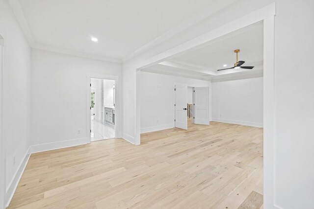 unfurnished living room featuring light hardwood / wood-style flooring, ceiling fan, and a raised ceiling