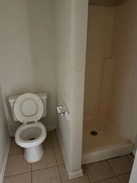 bathroom featuring tile flooring, toilet, and a shower