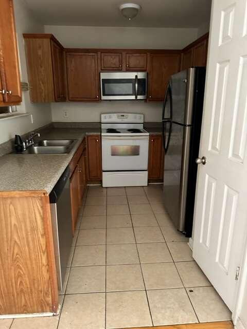 kitchen with stainless steel appliances, sink, and light tile flooring