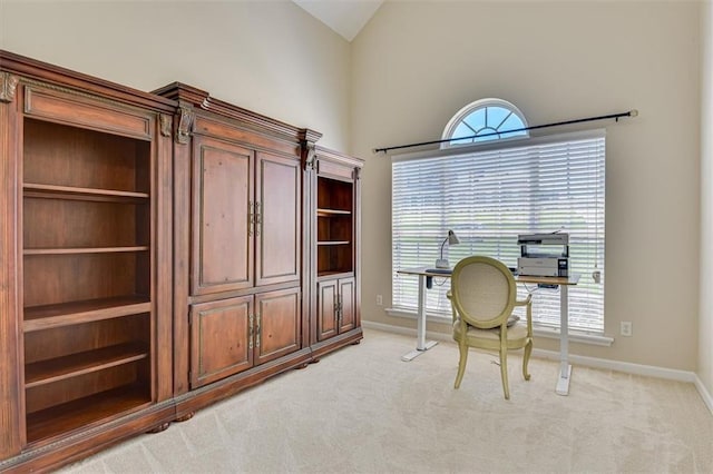 office space featuring baseboards, vaulted ceiling, and light carpet