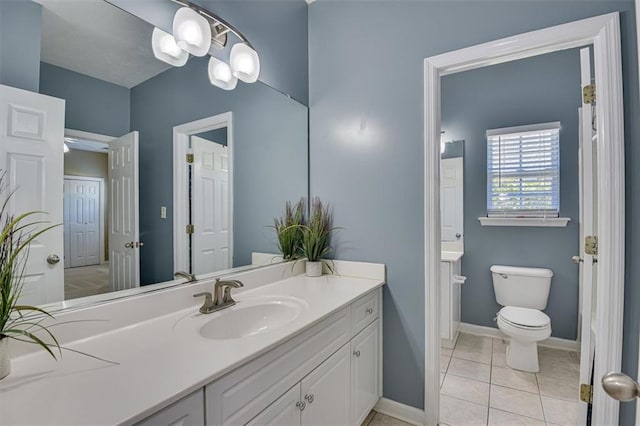 bathroom featuring vanity, baseboards, toilet, and tile patterned flooring