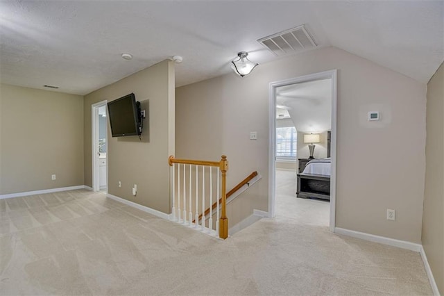 hall featuring an upstairs landing, light colored carpet, lofted ceiling, and baseboards