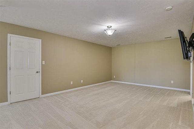 spare room featuring light carpet, baseboards, a smoke detector, and a textured ceiling