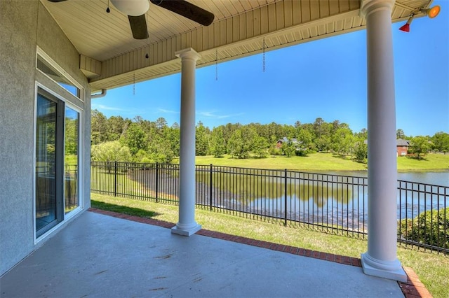 view of patio featuring a water view, a ceiling fan, a fenced backyard, and view of wooded area