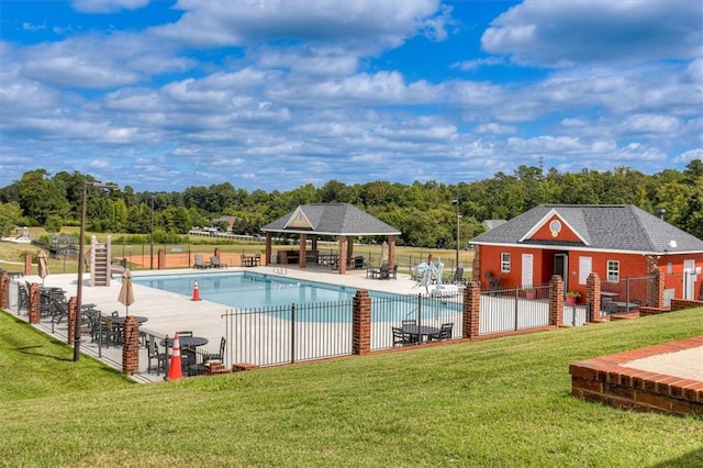 community pool with a gazebo, a patio area, an outdoor structure, and view of wooded area