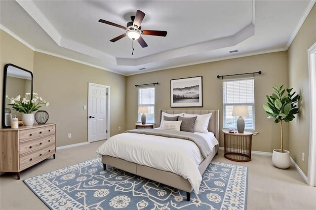 carpeted bedroom featuring a raised ceiling, crown molding, baseboards, and a ceiling fan